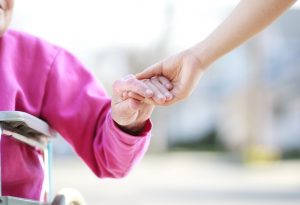Stock image of an elderly woman holding hands